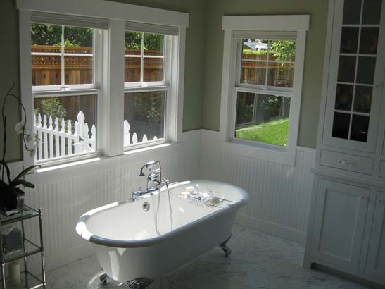 Standalone bathtub with vintage stainless steel fixture on a standard white lenolium tile floor