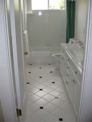 Different angle of White tile with small black tile patterned bathroom, with white cabinetry