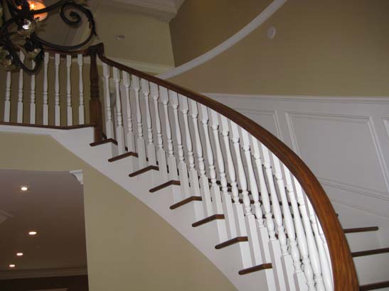 After photo of the finished product - white stairs with deep brown steps and a white trimmed wall behind it.